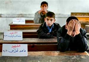 Palestinian boy Mohammed kutkut, 14, right, covers his face as he sits next to the name sign of his killed friend Ahed Qaddas in the Fakhoura boys school in Jebaliya, northern Gaza strip, Jan. 24. Three friends in his class were killed when the Israeli army shelled Jebaliya in the past weeks 