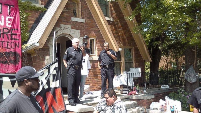 High-ranking Detroit police stand guard over the eviction of Jeanette Shannon. The bailiff is standing between the two uniformed officers.