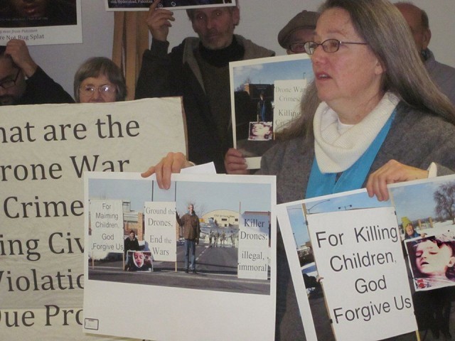 Mary Ann Grady Flores holds photos she was arrested for taking at Hancock AFB anti-drone protest.WW photo: Minnie Bruce Pratt