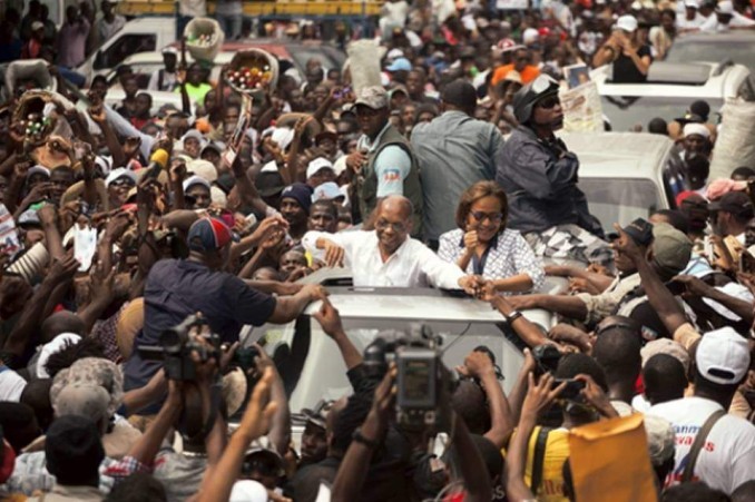 Haiti's former President Jean-Bertrand Aristide waves to supporters as he campaigns with presidential candidate Maryse Narcisse of the Fanmi Lavalas political party, in Petion-Ville, Haiti, Monday, Aug. 29, 2016.
